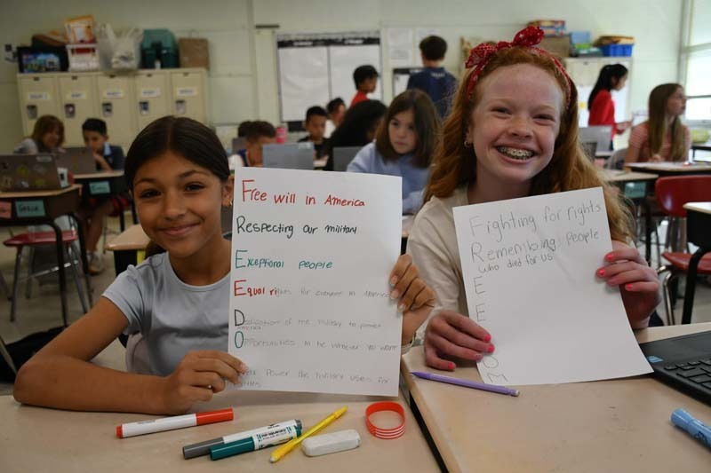 Students smiling at the camera, holding their projects.