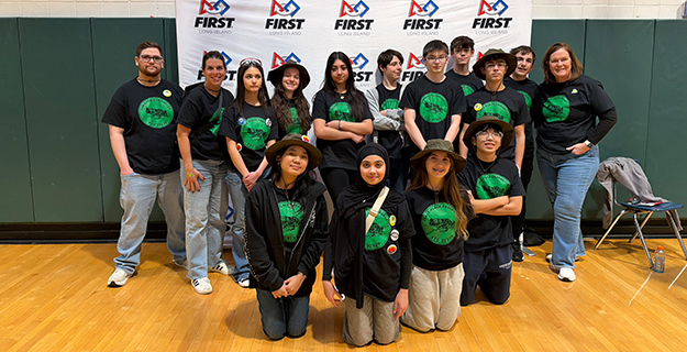 Students and teachers standing in front of FIRST banner.