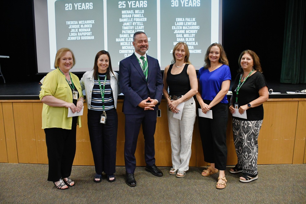 Teachers in front of projector displaying years of tenure.