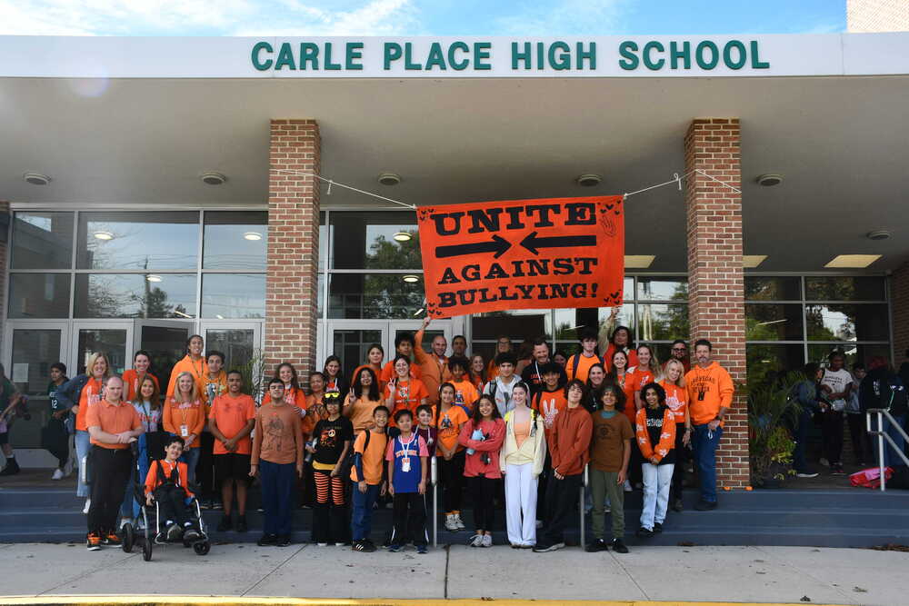 Students dressed in orange holding sign saying Unite Against Bullying!
