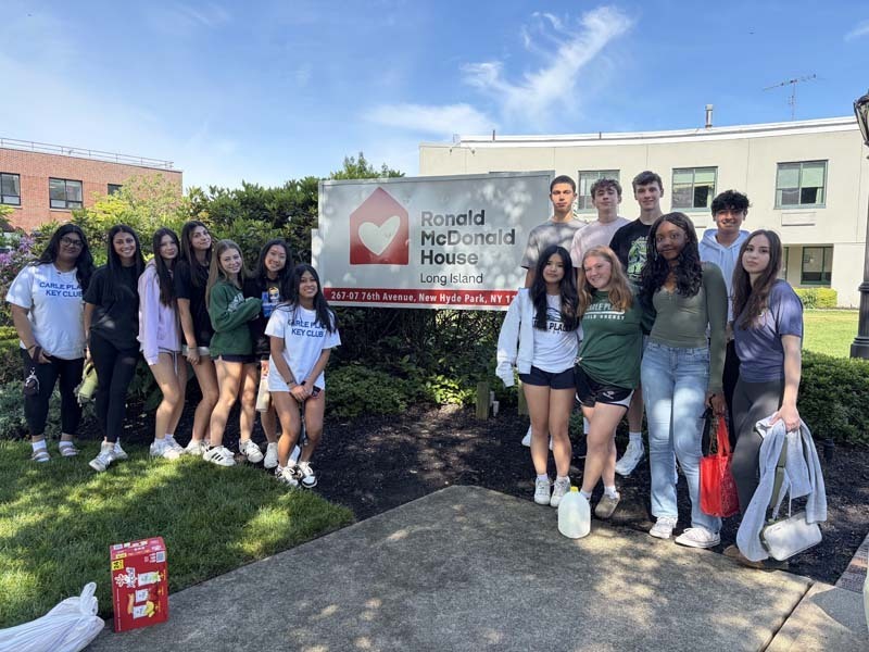 Students smiling outside by Ronald McDonald foundation banner.