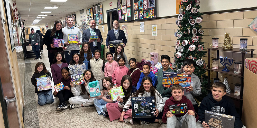 A group of students and adults in a school hallway hold toys and games