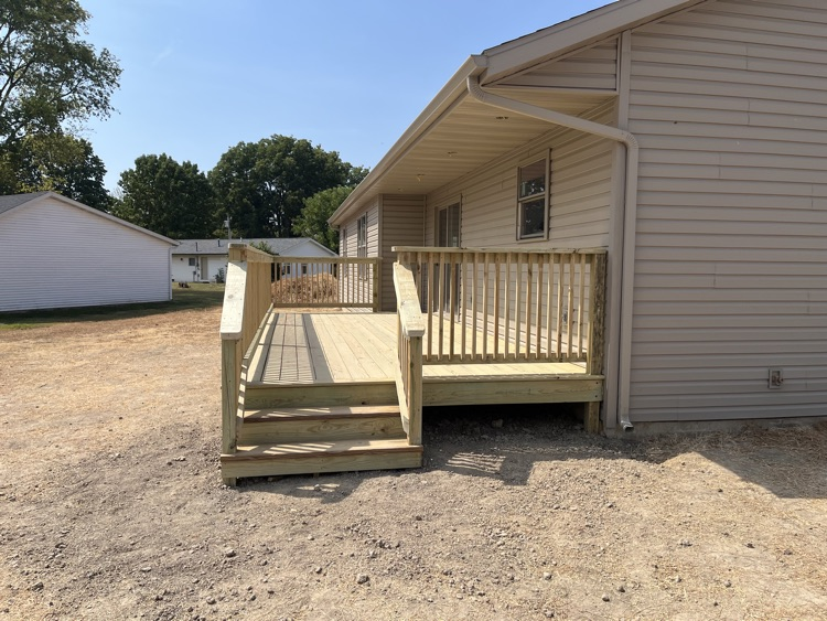 a photo of a wood deck attached to a tan house