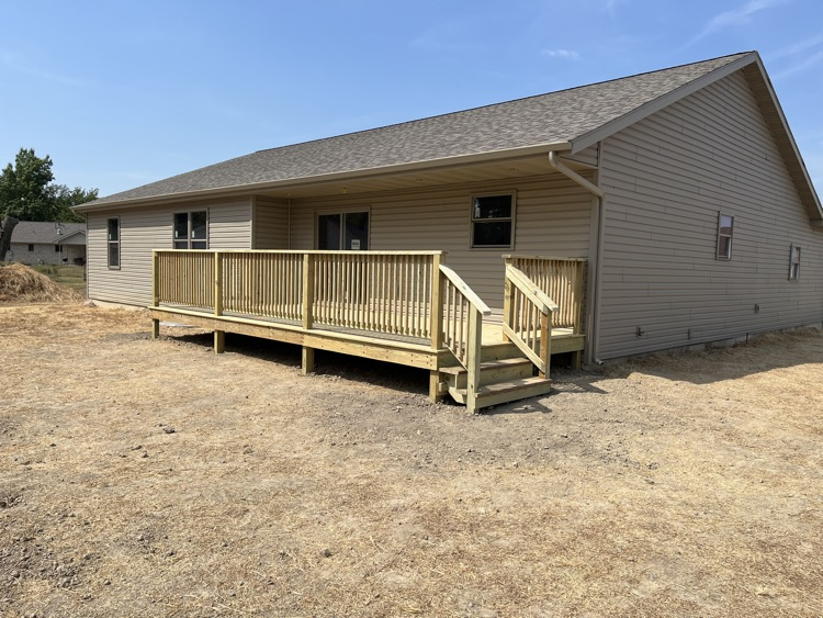 a photo of a wood deck attached to a tan house