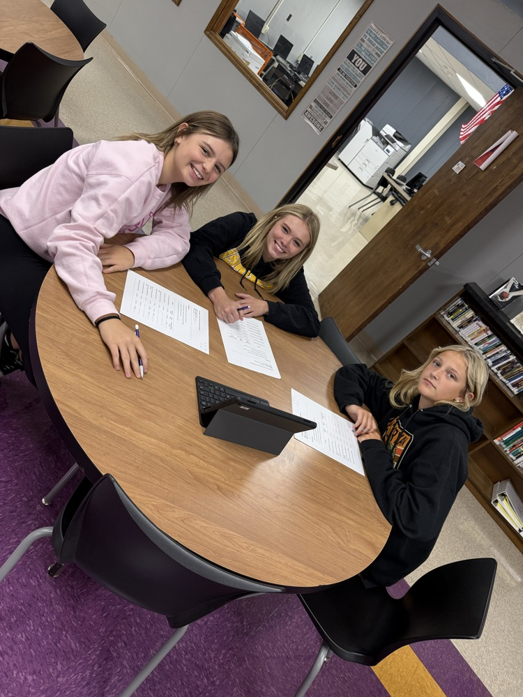 3 girls sit together at a library table to study