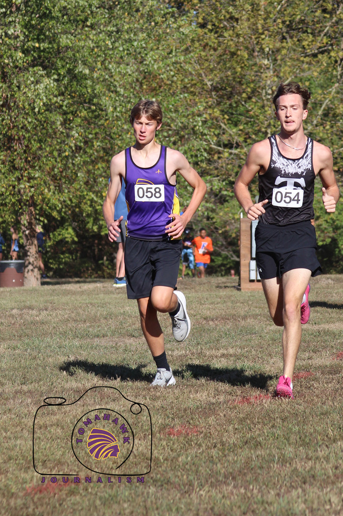 Benson and another boy run through a field.