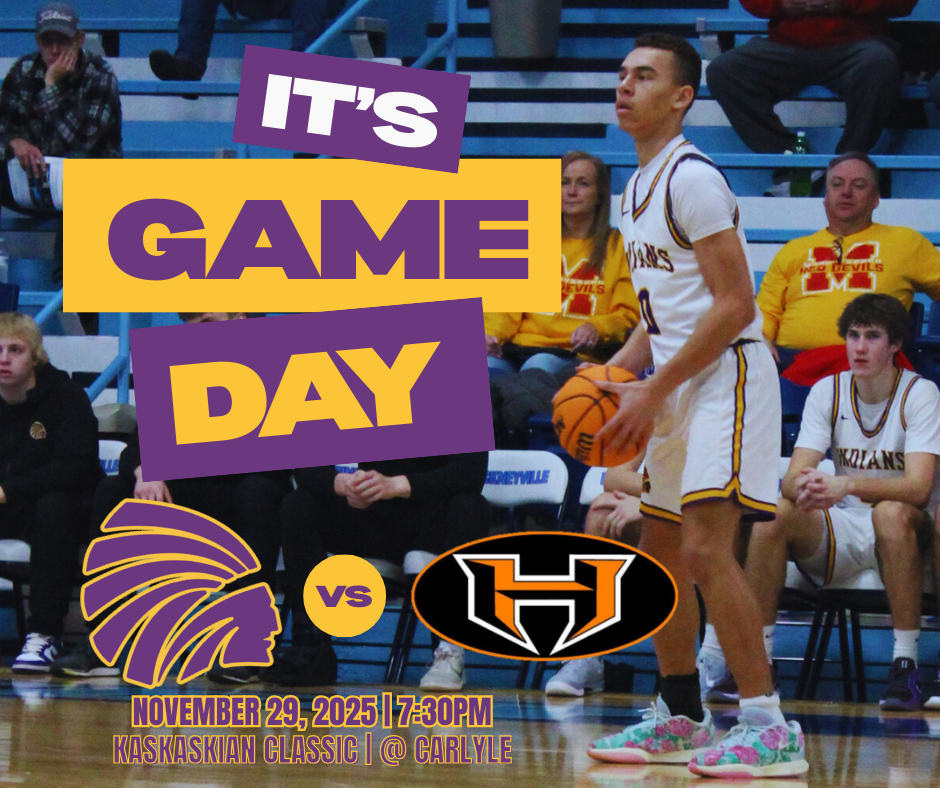  A purple and gold basketball game day graphic. The text reads "It’s Game Day" and "November 29, 2025 | 7:300 PM | Kaskaskian Classic | @ Carlyle." A basketball player in a white and gold uniform is shown on the court holding a ball, standing in front of spectators in the bleachers. The graphic also features the Indian head logo,a "vs" icon, and the Hillsboro Toppers Mascot