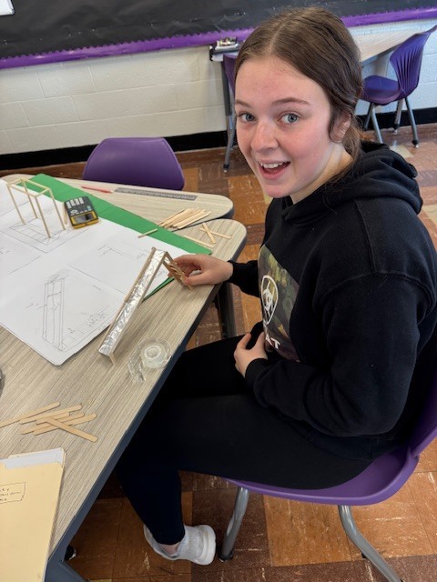 A female student smiles while creating a slide