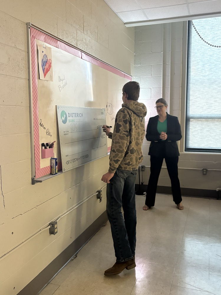 students practices filling out a large check
