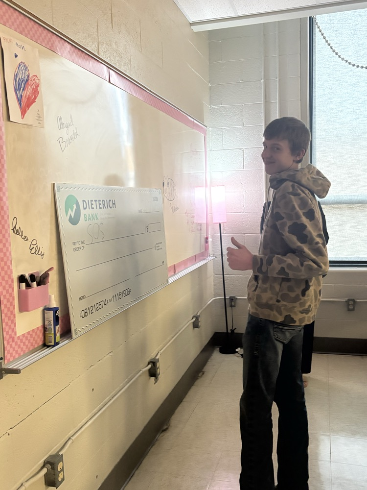 student gives a thumbs up by the large check
