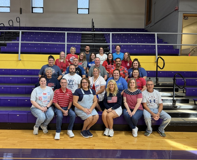 Group photo of all staff members in the gymnasium, wearing red white and blue