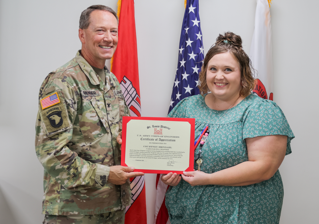 Ibendahl smiles holding certificate with US Army Corp of Engineers