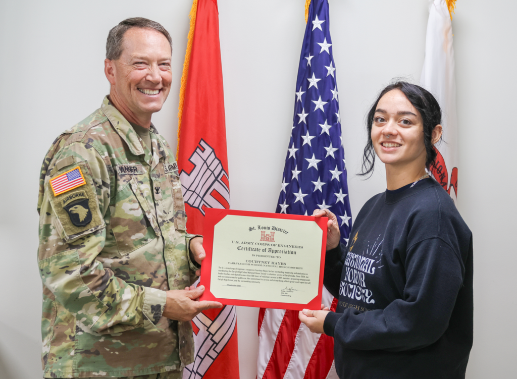 Hayes smiles holding certificate with US Army Corp of Engineers