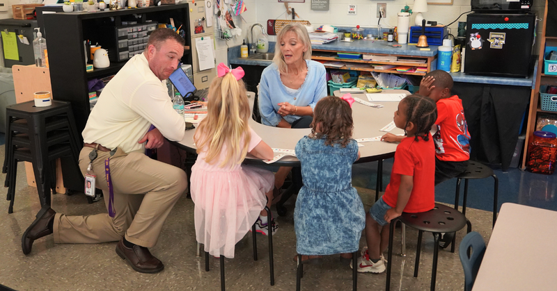 a teacher leads a group of young students