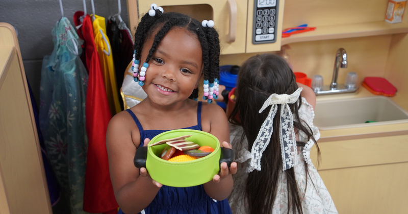 a student shows off the play food she is cooking