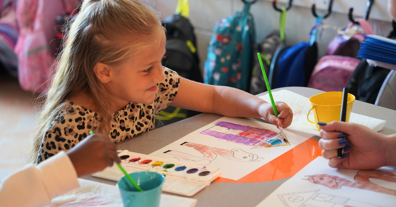 a young girl paints with water colors