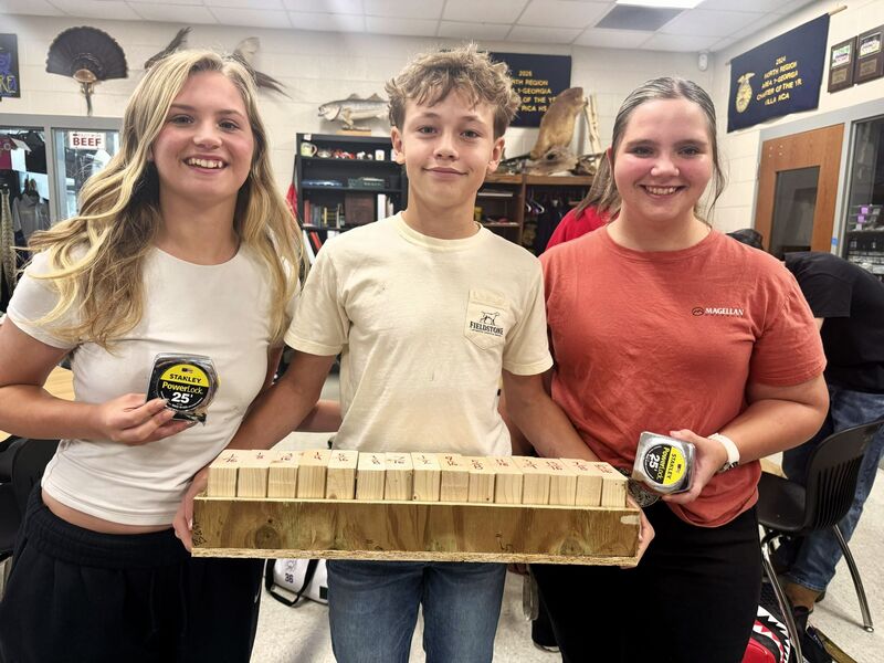 three students poses with lumbar and tape measures