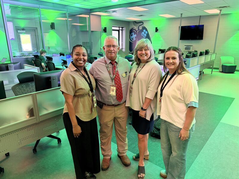 four people pose for a photo in a computer science lab