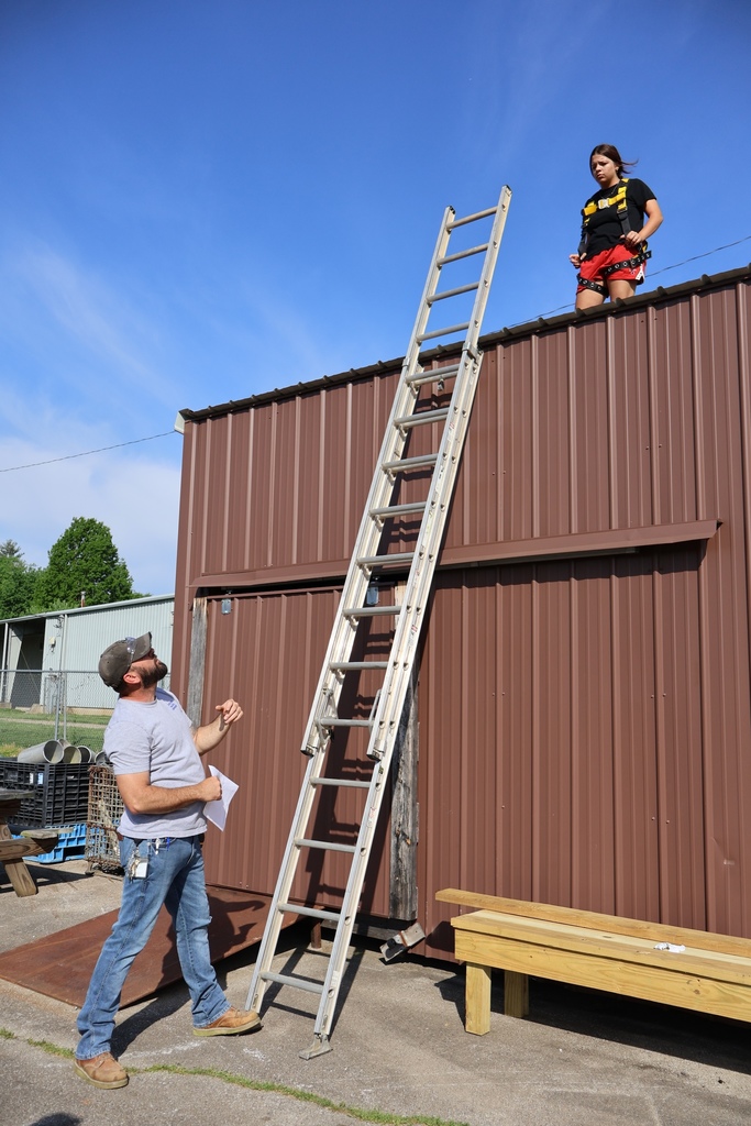 Teacher telling student how to climb onto ladder and get off roof