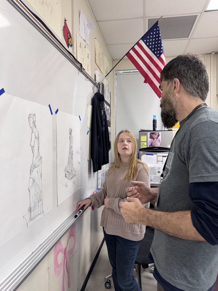 student and art teacher discussing drawings