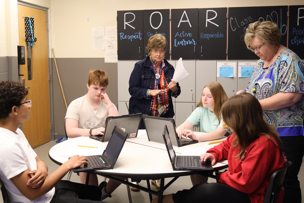 Adults working with students on presentation