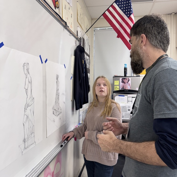 student and art teacher discussing drawings