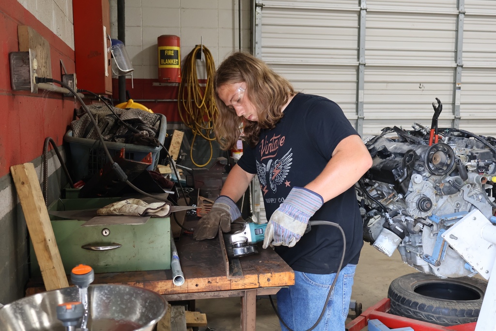 student using grinder in auto shop