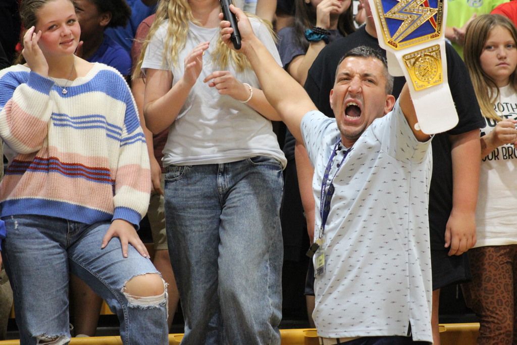 Photo of Coach Laswell holding a microphone and a W W E belt.