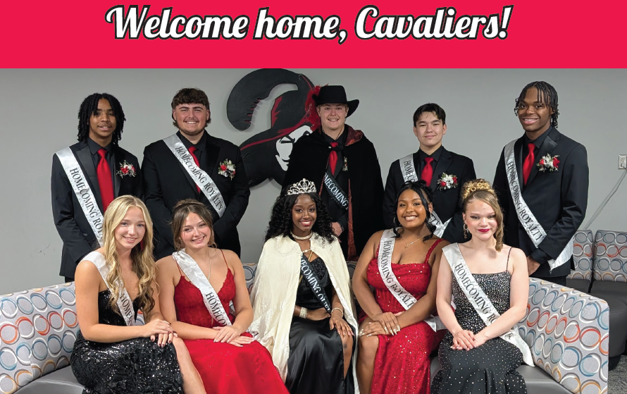 A group of Homecoming Court students pose together in formal attire inside a school lounge. Four students wearing suits, ties, and Homecoming Court sashes stand in the back row. Five students wearing formal gowns and sashes sit in the front row on patterned couches. The Homecoming Queen, wearing a crown and a white cape, sits in the center. Behind them is a large mural of the Carrollton Cavaliers mascot. At the top of the image, bold white text on a red background reads, “Welcome home, Cavaliers!”