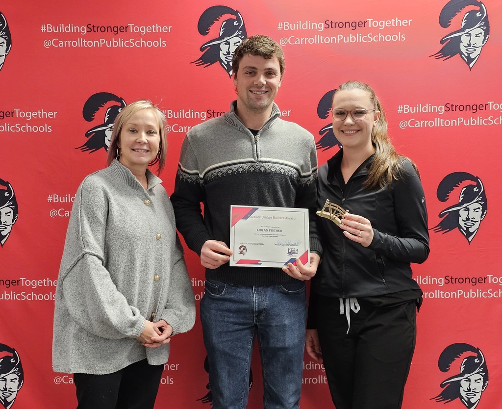 Three people stand smiling in front of a red CPS backdrop featuring the Cavalier logo and the hashtag #BuildingStrongerTogether. In the center, a man holds a Cavalier Bridge Builder Award certificate. To his left stands a woman, and to his right another woman holds a small bridge-shaped award.