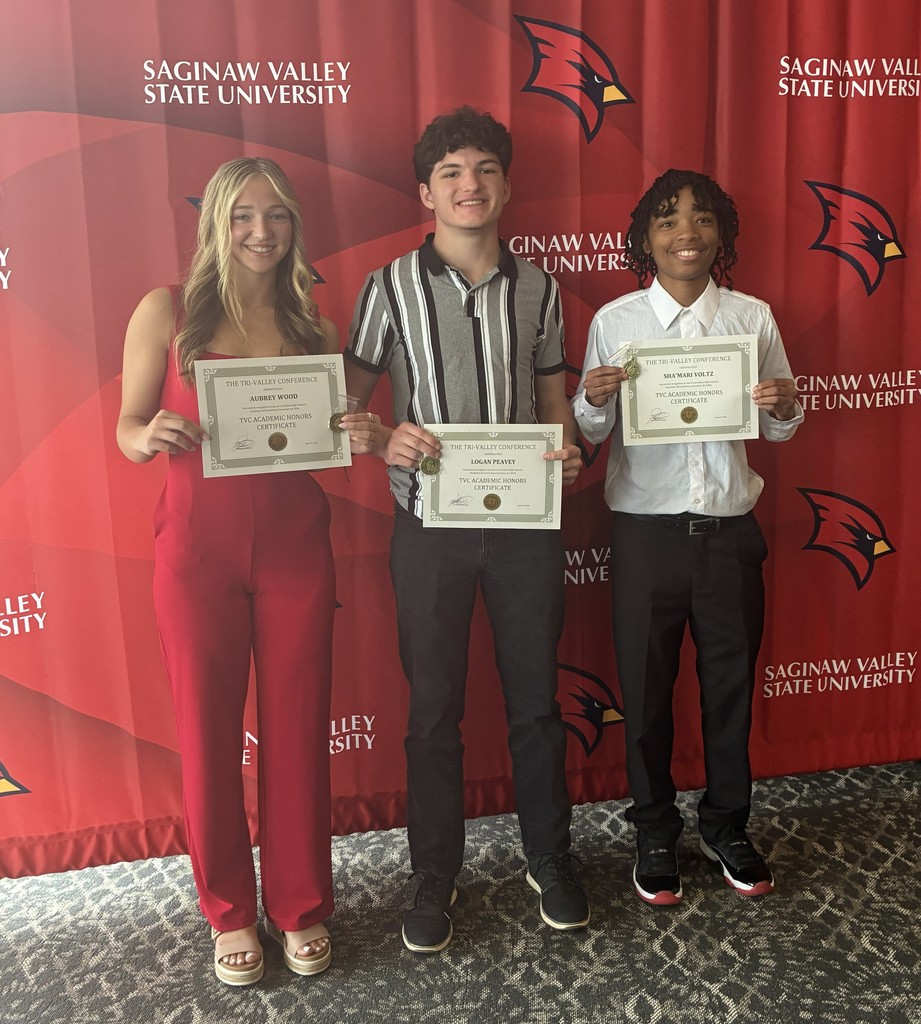 Three high school students stand side by side in front of a red Saginaw Valley State University backdrop with Cardinal logos, smiling and holding “TVC Academic Honors Certificate” awards. The student on the left wears a red outfit, the student in the middle wears a striped shirt, and the student on the right wears a white button-down shirt and dark pants. All three are posing proudly to celebrate their academic achievements.