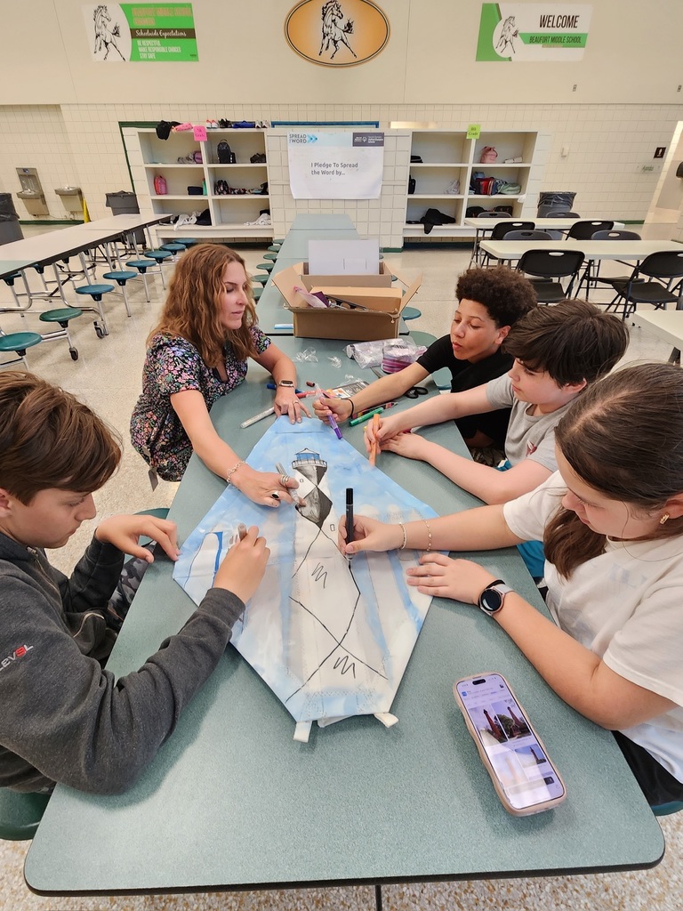 students and staff painting a boat