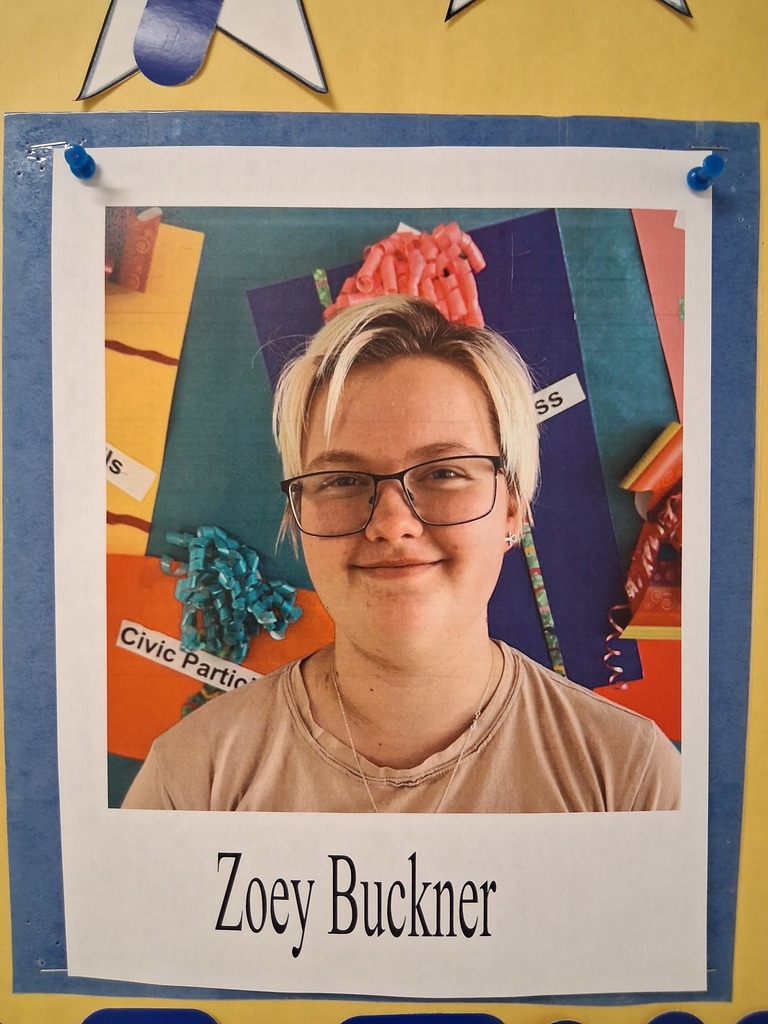 Zoe Buckner, stands in front of a colorful background, smiling for a portrait. 