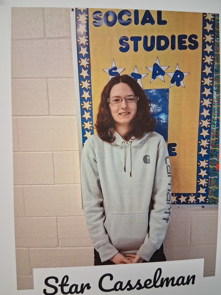 Star Casselman stands in front of the Social Studies All Star bulletin board.