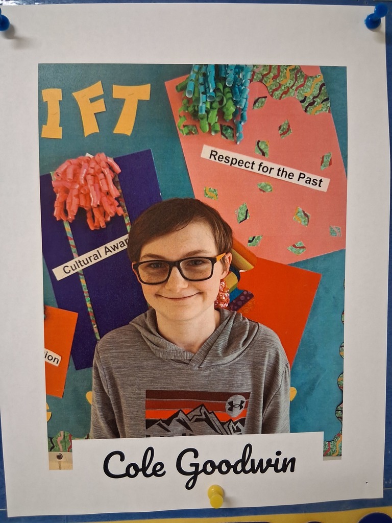 Cole Goodwin smiles in front of a colorful bulletin board.