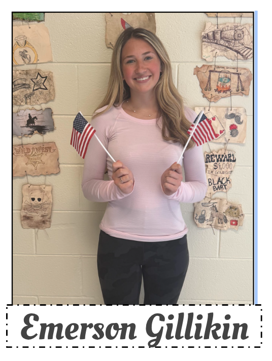 Emerson Gillikin stands by a wall  holding two American flags.