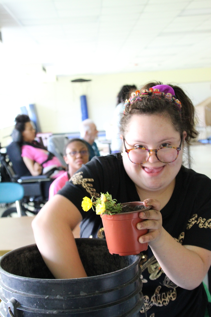 Sky adds dirt to her plant.