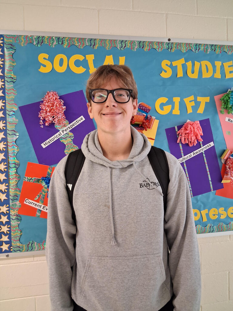 William Lewis stands in front of a colorful bulletin board.