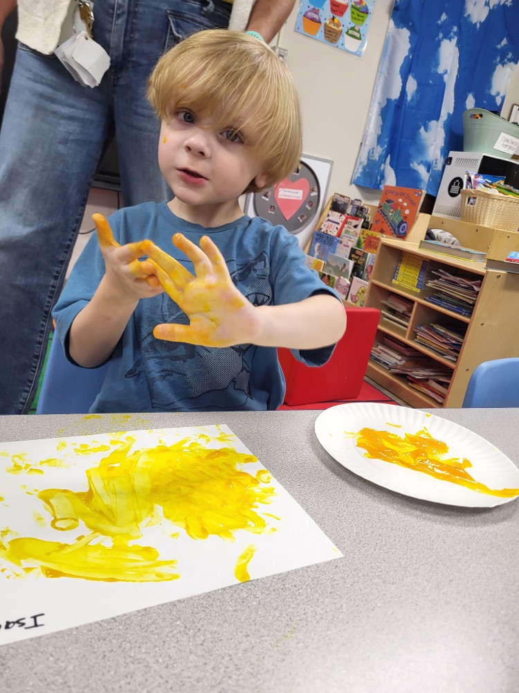 child fingerprinting with yellow paint 