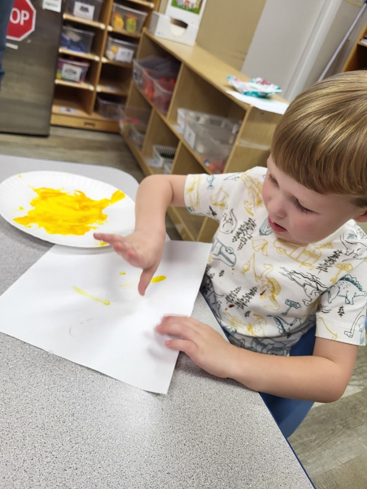 child fingerprinting with yellow paint 