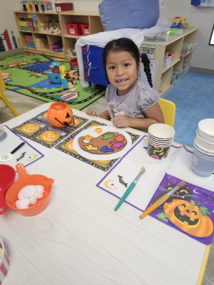 little girl smiling and working at a table in preschool