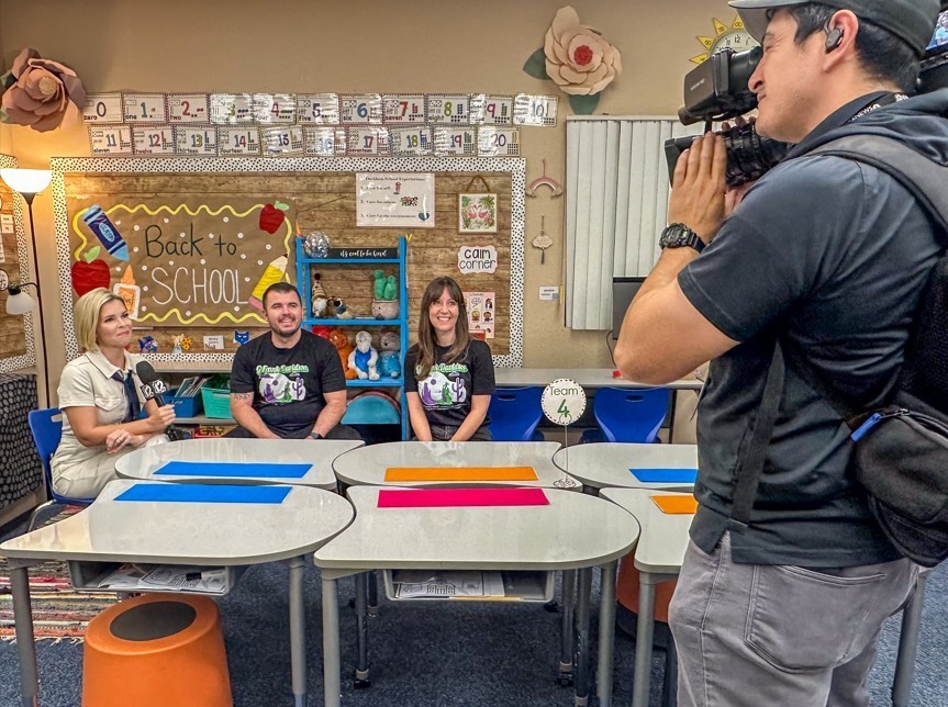 Camera man and reporter interviewing a man and a woman