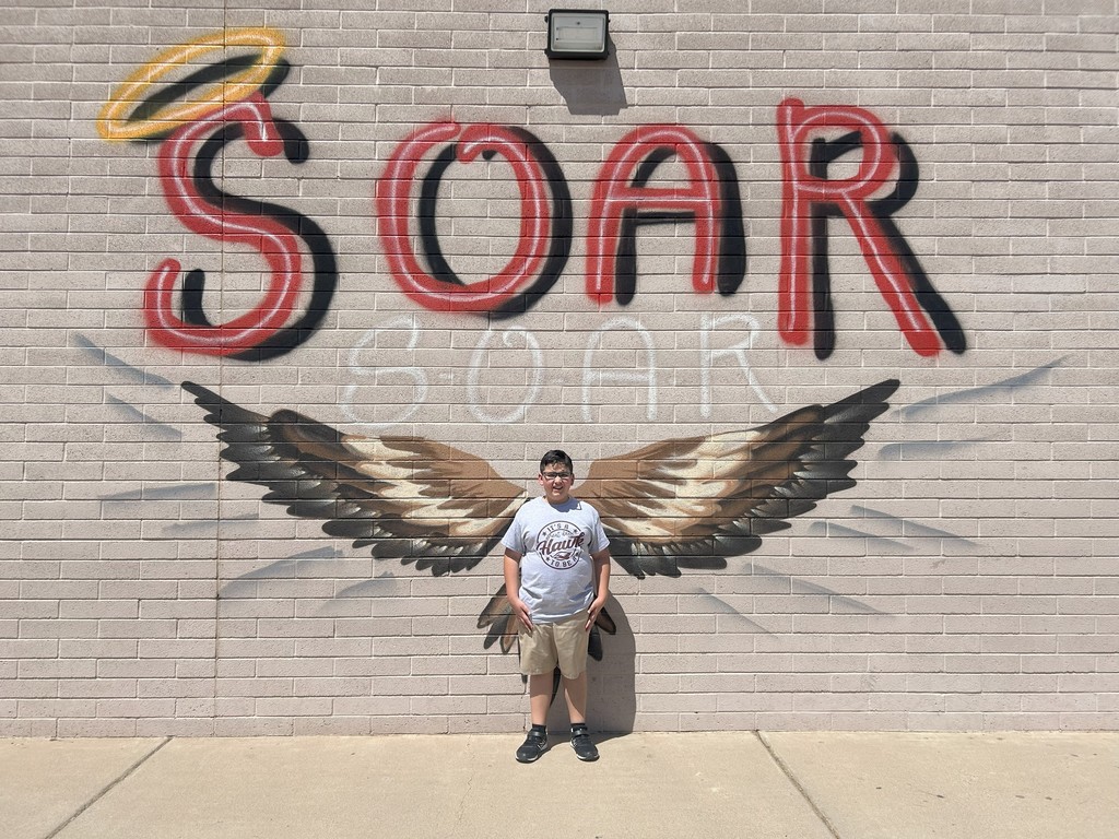 student standing in front of school mural 