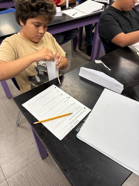 Students focused on constructing a tall, free-standing tower using only white paper and tape, applying the STEM Design Process.