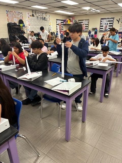 Students focused on constructing a tall, free-standing tower using only white paper and tape, applying the STEM Design Process.