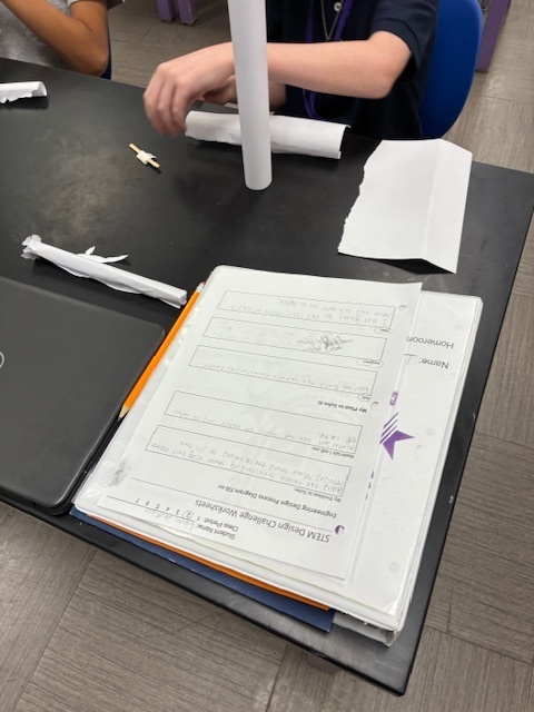 Students focused on constructing a tall, free-standing tower using only white paper and tape, applying the STEM Design Process.