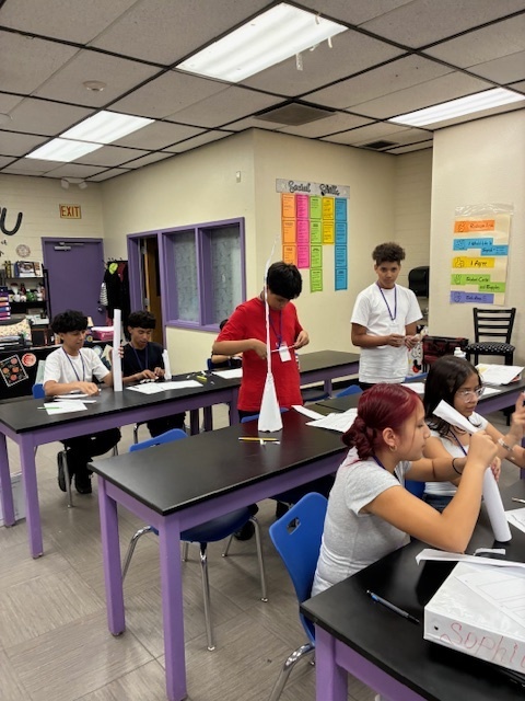 Students focused on constructing a tall, free-standing tower using only white paper and tape, applying the STEM Design Process.