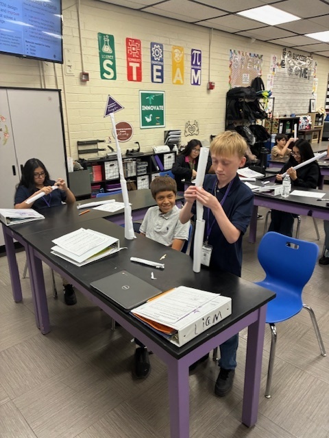 Students focused on constructing a tall, free-standing tower using only white paper and tape, applying the STEM Design Process.
