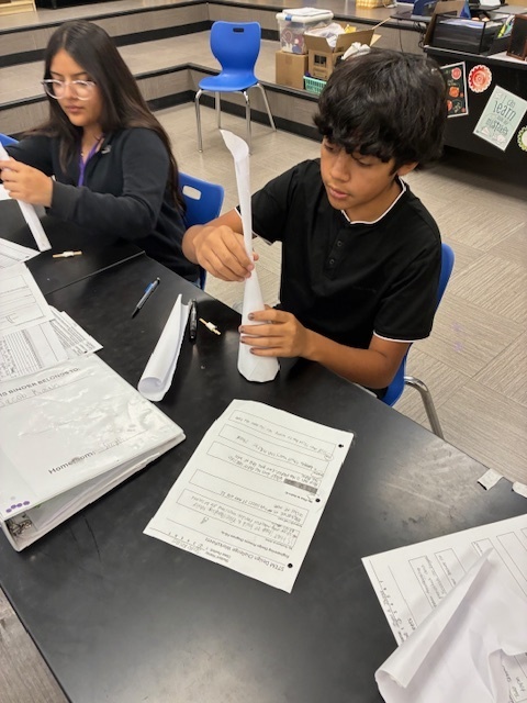 Students focused on constructing a tall, free-standing tower using only white paper and tape, applying the STEM Design Process.