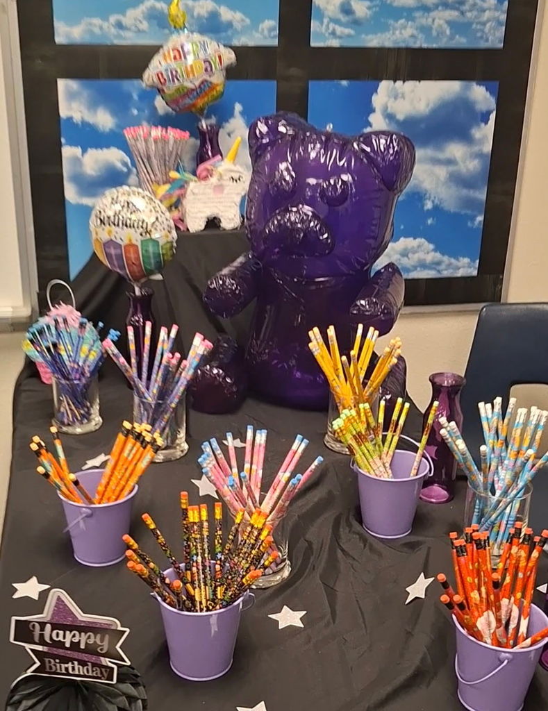 Birthday prize table decorated with balloons and stacked gifts for students and teachers at Estrella Middle School